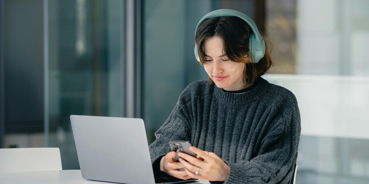 woman on laptop looking at smartphone